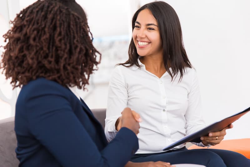 duas mulheres apertam as mãos em sinal de sucesso de uma comunicação focada no cliente